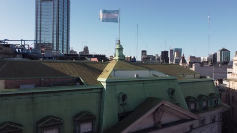 argentinian flag waving on roof of argentine nation bank building with skyscraper in background