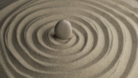rotación de la piedra blanca en el centro de la espiral de arena. primer plano de los patrones en la arena