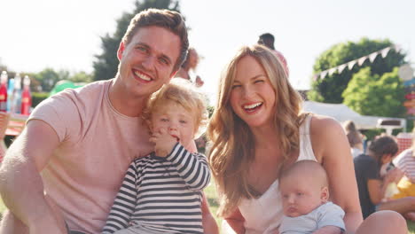 slow motion portrait of family with children sitting on grass at summer garden fete