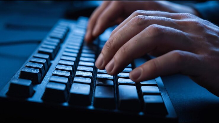 Nærbillede af hænder, der taster på et oplyst mekanisk tastatur under en natlig programmerings- og gaming-session