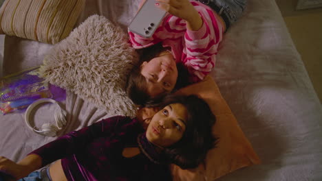 two girls taking a selfie on a bed
