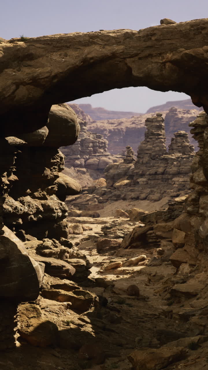 Vast rocky landscape featuring a natural stone arch against clear skies