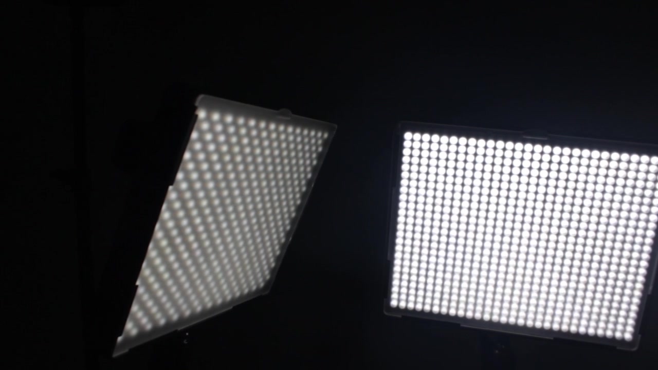 Due pannelli luminosi a LED emettono luce intensa in un ambiente di studio buio, creando un netto contrasto. Ideale per l'uso nella progettazione illuminotecnica o in contesti di produzione cinematografica.