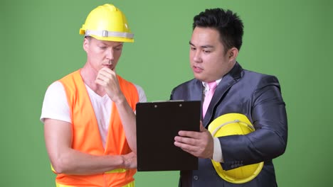 scandinavian man construction worker and asian businessman working together