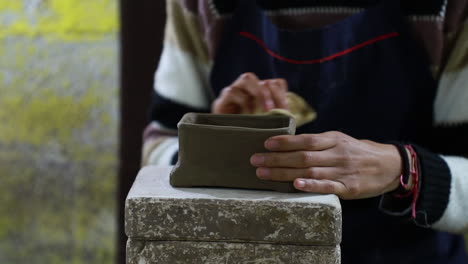 Close-up-over-the-hands-of-a-mexican-craftswoman-moistening-the-final-part-of-a-clay-craft