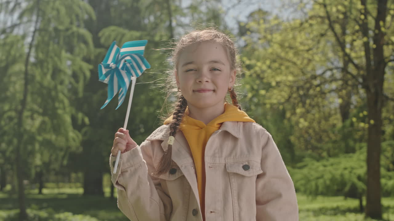 Portrait of Happy Girl with Pinwheel Toy in Park