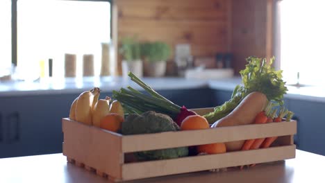 crate of organic vegetables on countertop in sunny kitchen, slow motion