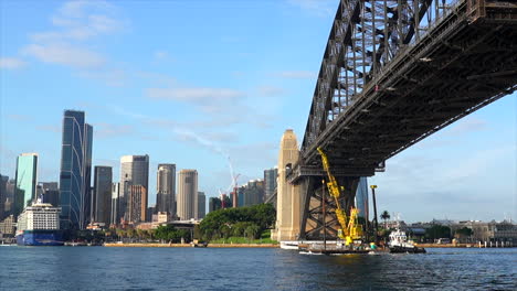 a construction crane ship passes underneath sydney harbour bridge in australia