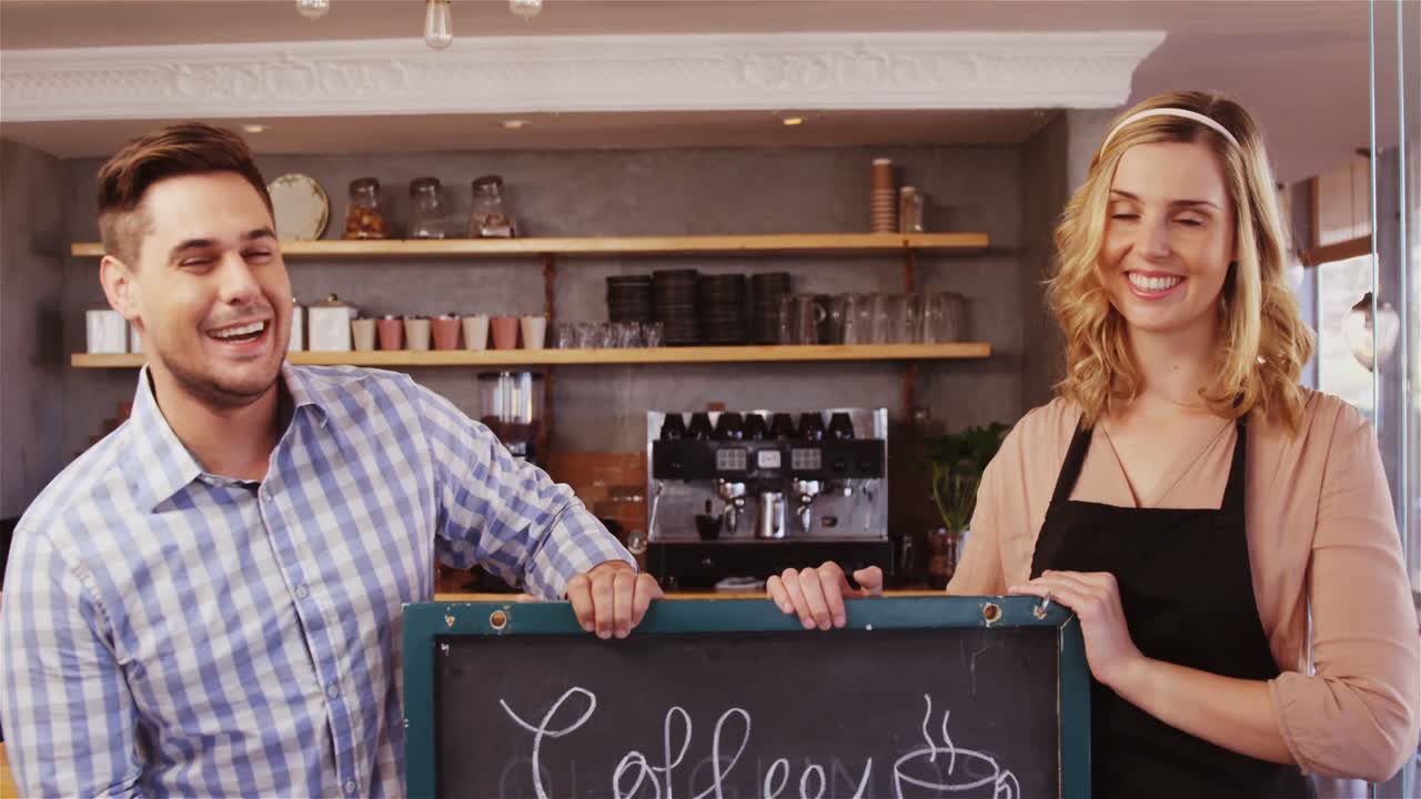 Waitress and man standing with coffee sign in caf&Atilde;&copy;