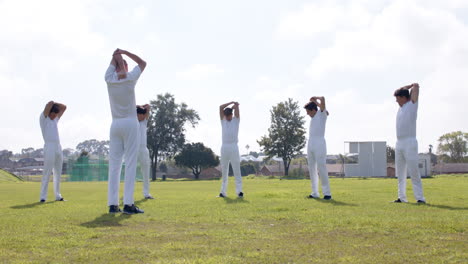 team of male cricket players practicing cricket wearing cricket whites on pitch