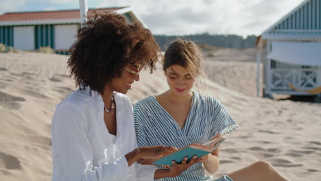 Zwei-Mädchen-Lesen-Buch-Beim-Picknick-Am-Strand-Im-Sommer.-Glückliches-Lesbisches-Paar-Im-Gespräch