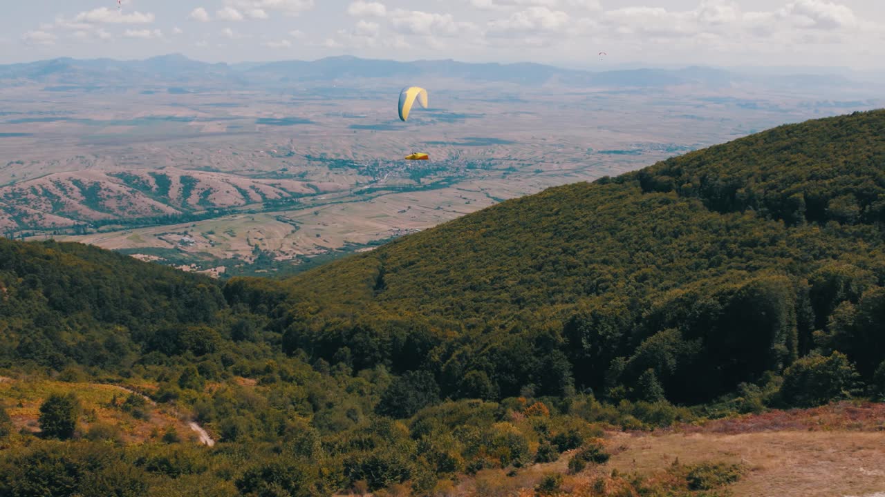 패러글라이딩 전문가 가 숲 위 에 있는 공중 을 통해 평화롭게 글라이딩 하고 있다