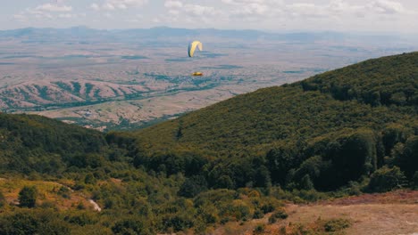 paragliding expert gliding peacefully through the air above a forest