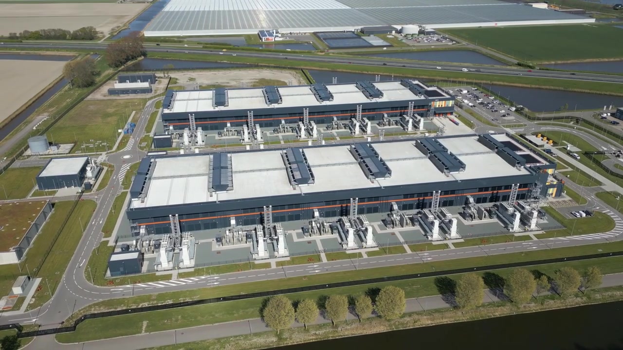 Low aerial drone footage capturing cooling systems and industrial infrastructure of a large scale data center facility.