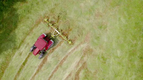 red lawn mower moving in field trimming overgrown grass