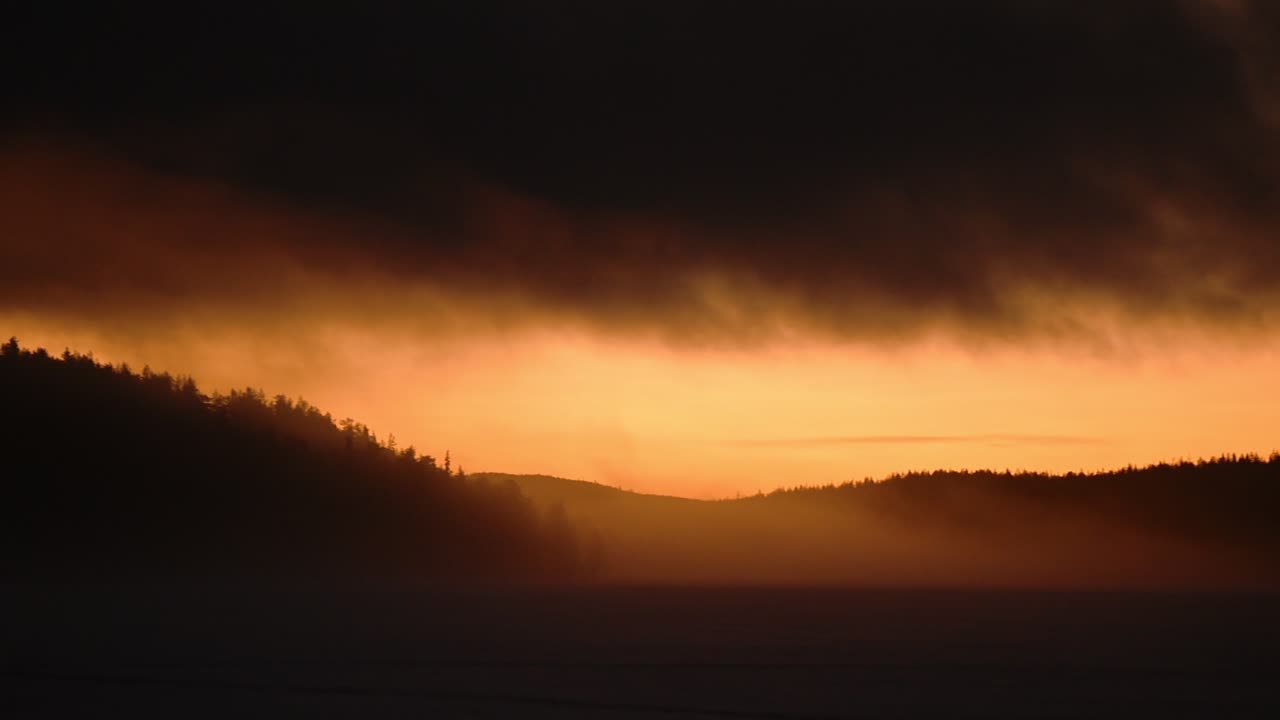 Panoramic landscape view of a orange sunrise over a frozen lake, on a misty morning, in Lapland, Finland