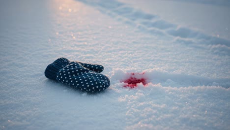 a single mittens left behind in the snow with a mysterious red spot nearby, evoking a sense of intrigue and suspense in a winter landscape