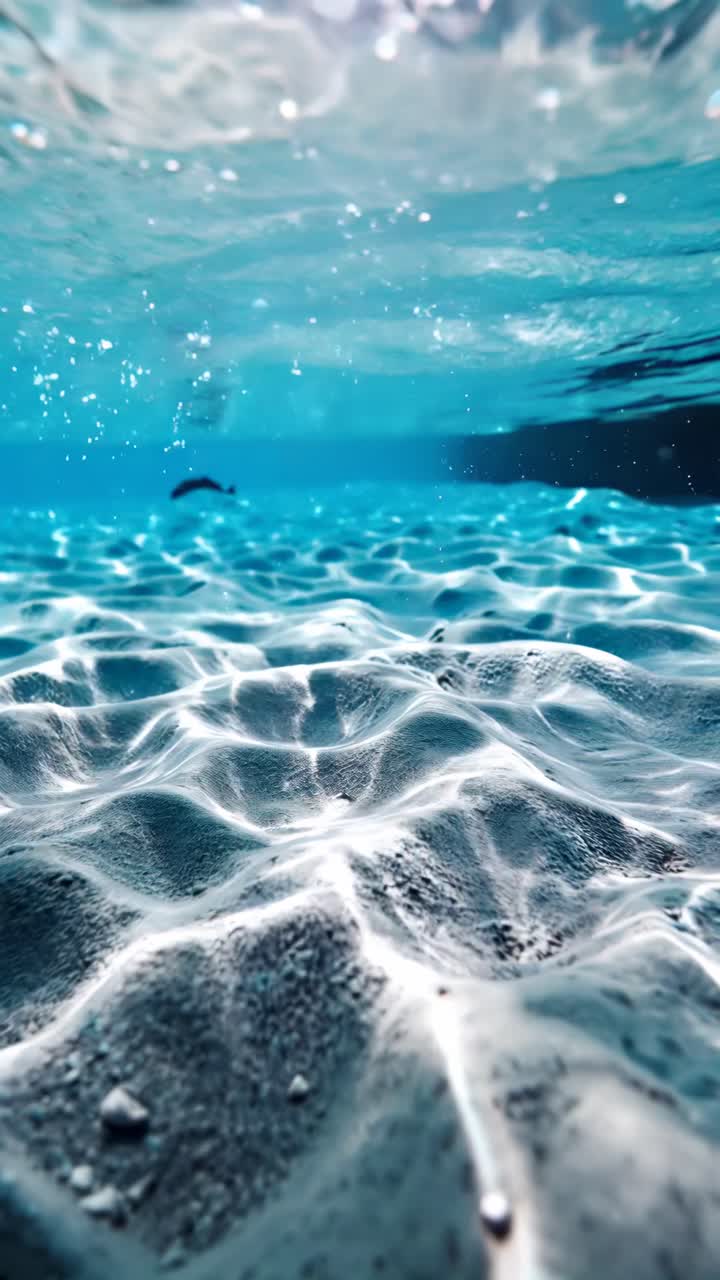 Concept di video subacqueo con ripresa dal basso che cattura i giochi di luce solare sul fondale sabbioso dell'oceano