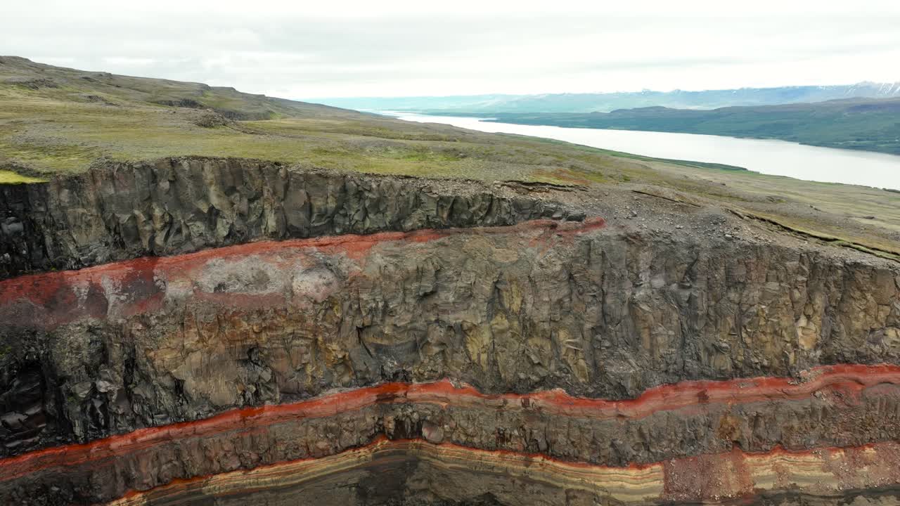 Aerial Revealing shot of hengifoss waterfall and fjord river on Iceland. Wide shot. Landscape and hills on volcanic island. Summer season