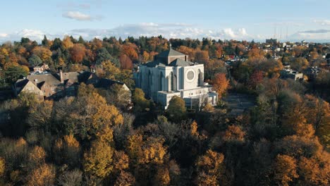 drone retiro de órbita por encima de la hermosa catedral rodeado de fuego rojo naranja follaje de otoño, washington