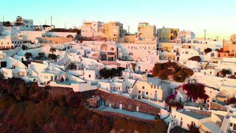toma aérea cinematográfica del famoso pueblo de oia en santorini, grecia, al atardecer