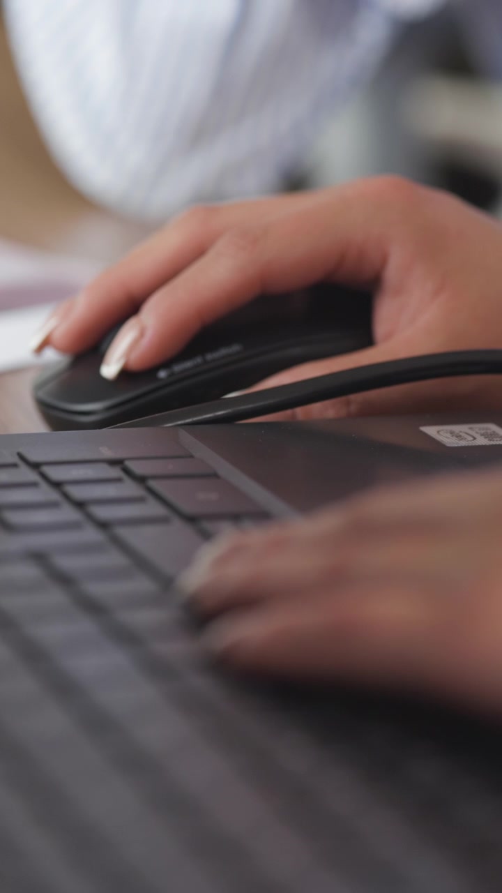 Primo piano che mostra una mano sul mouse e l'altra sulla tastiera del laptop