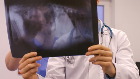 el veterinario está hablando con su asistente sobre una radio de rayos x.