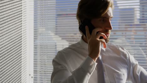 Front-view-of-young-Caucasian-male-executive-talking-on-mobile-phone-in-a-modern-office-4k