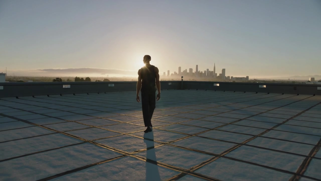 Walking silhouetted man moving from skyline toward camera, sunrise urging motion with rooftop grid