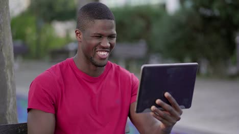 man watching football match on tablet in park, celebrating goal