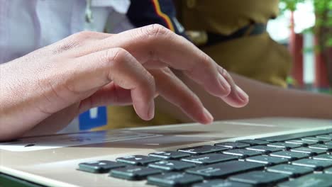 A-Sailing-and-Maritime-Vocational-School-student-does-schoolwork-in-the-school-garden,-She-is-using-a-touchpad-on-her-laptop,-he-does-assignments-and-is-directed-by-his-teacher