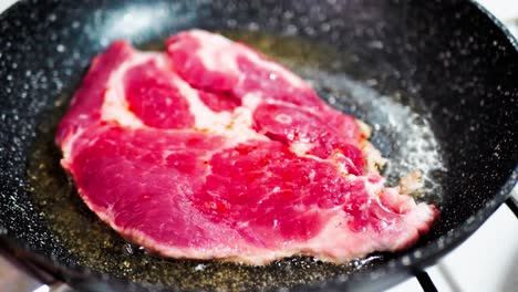 fresh beef meat on ignited pan with salt and pepper and spices, closeup view. cooking beef steak at frying pan, delicious steaks are fried on a grill pan.