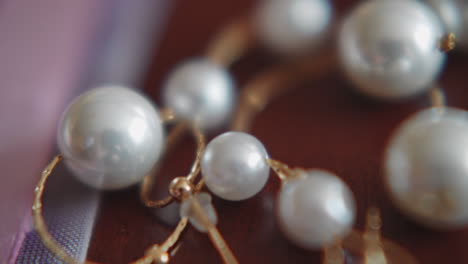 Golden-earring-with-sparkling-pearls-and-chain-on-table