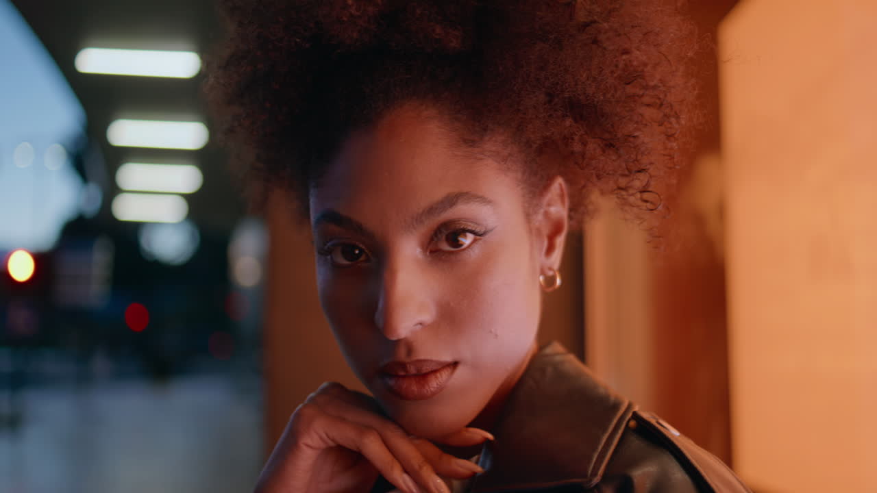 Woman face illuminated urban lights closeup. Portrait curly-haired model posing