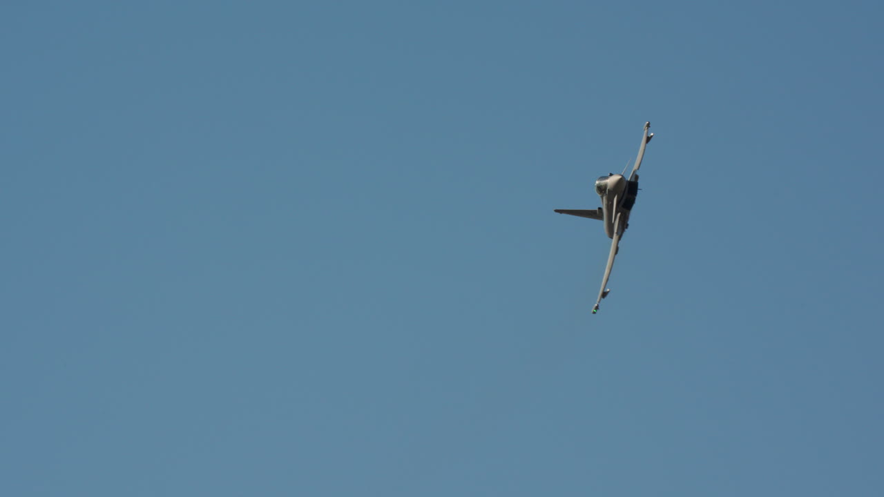 Caça realizando manobra dinâmica contra céu azul claro