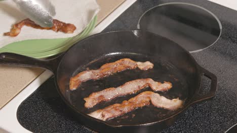 cast iron pan on stove removing bacon from hot pan