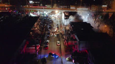 Empuje-De-Drones-En-Descenso,-Calle-De-Montreal-Por-La-Noche,-El-Edificio-Está-En-Llamas-Y-Los-Bomberos-Trabajan-Para-Apagarlo