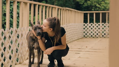 chica caucásica se pone en cuclillas junto a un perro tímido y le da besos