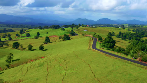 Vista-Aérea-De-La-Idílica-Carretera-Rural-Contra-El-Cielo-Nublado-En-Las-Mesetas-De-Atherton,-Queensland,-Australia---Disparo-De-Drones