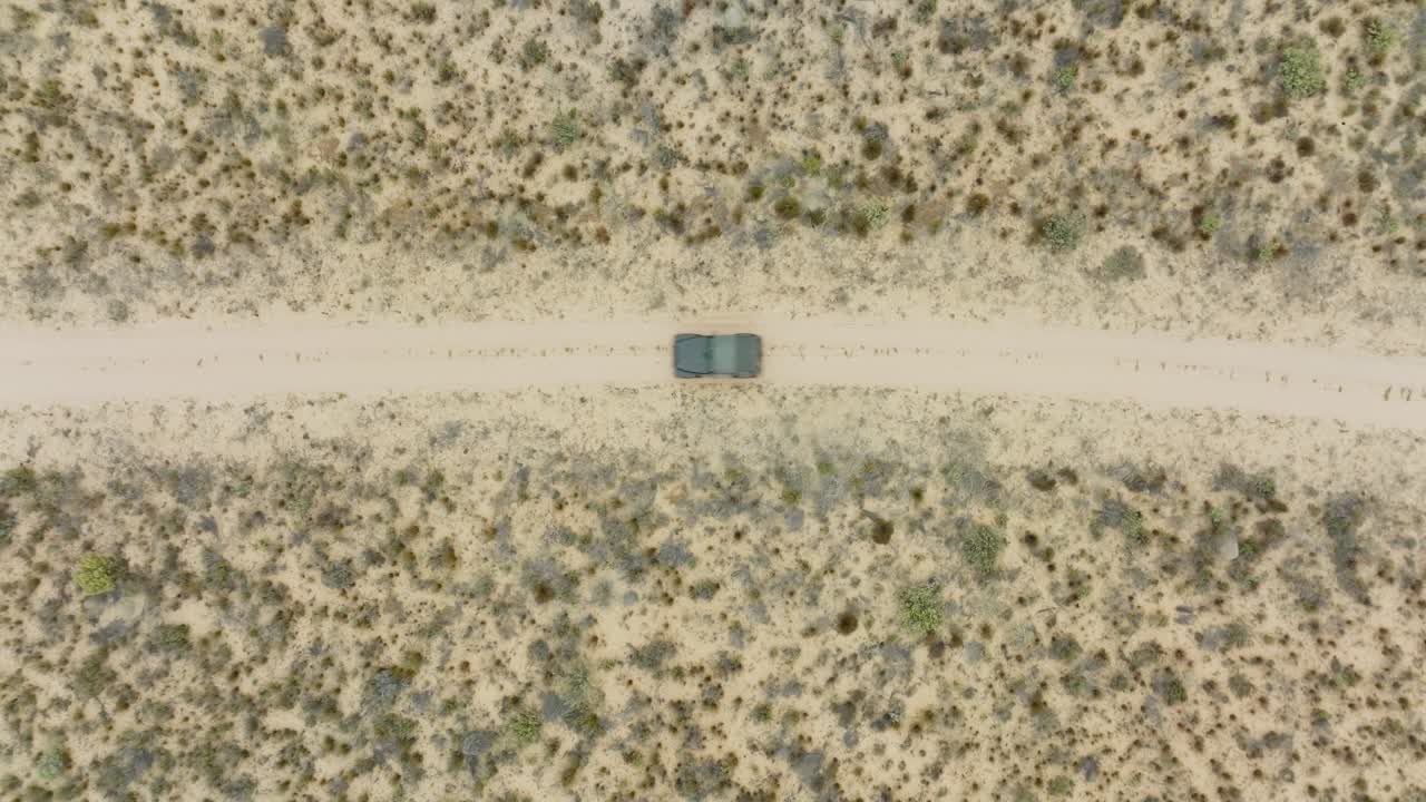 드론은 남아프리카의 cederberg wilderness 지역의 사막 풍경 위에서 새의 눈으로 날아다니며 검은색 오프로드 차량이 운전하는 사막의 도로 위에 있습니다.