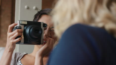 girl friends having fun hanging out at home using instant camera taking photos