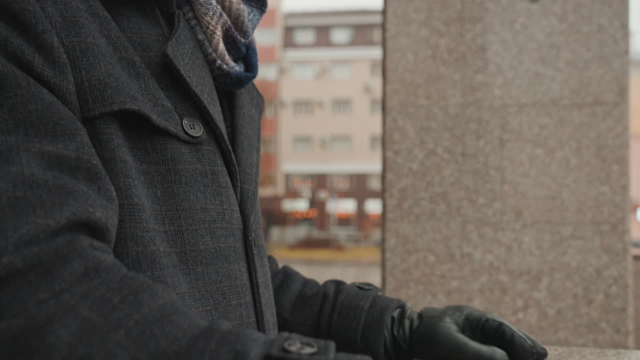 Young man seeks inspiration amid mist. Coated figure surveys skyline through morning fog. Young individual wearing coat and scarf searches for creative spark in urban morning atmosphere