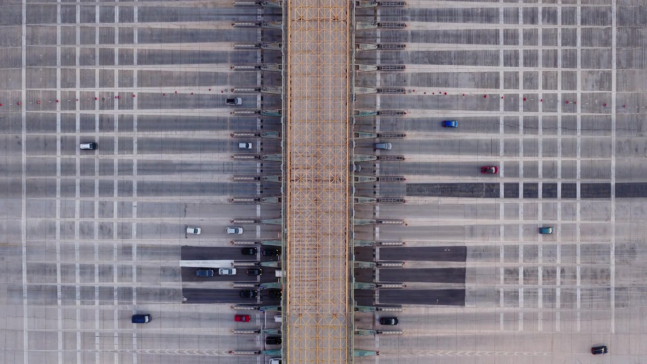 Descending top-down drone shot of Elefsina toll station, Greece. Cars crossing highway booths below. Cinematic overhead aerial infrastructure footage