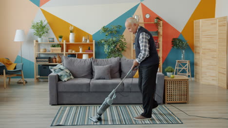 senior man vacuuming living room