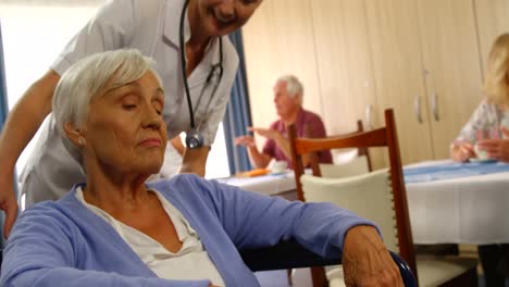 médico hablando con una mujer mayor sentada en silla de ruedas