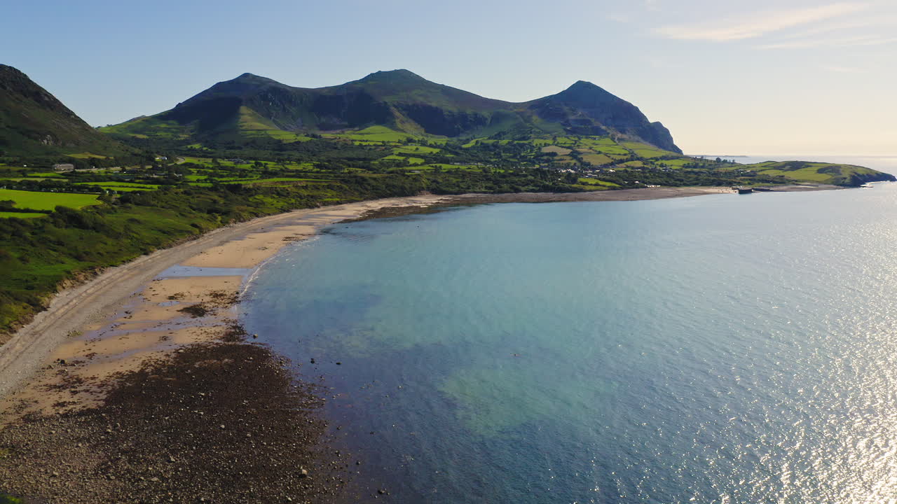 Stunning lush coast landscape of Wales with famous impressive Yr Eifl Mountains scenery in background of beach, aerial drone view