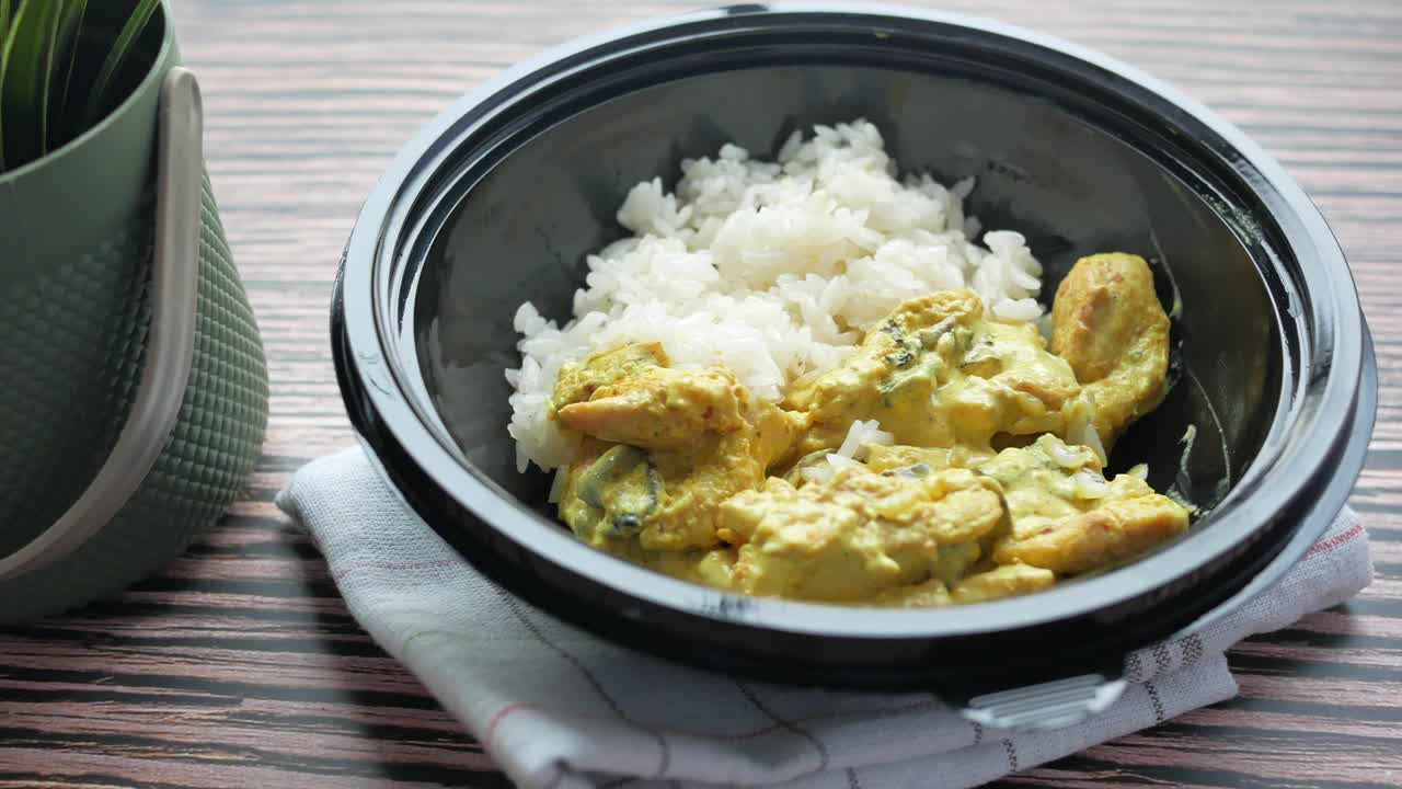 curry de pollo con arroz en un recipiente para llevar