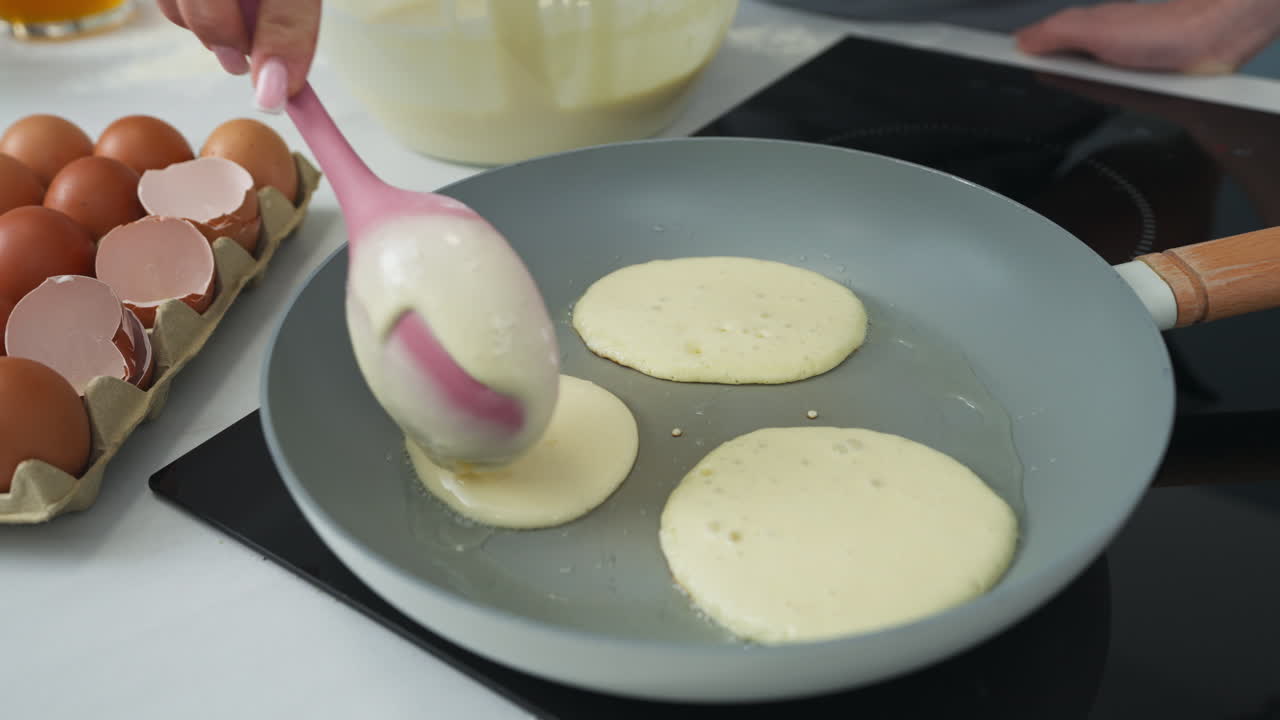 Pouring delicious pancake batter into the pan. Slow motion close up