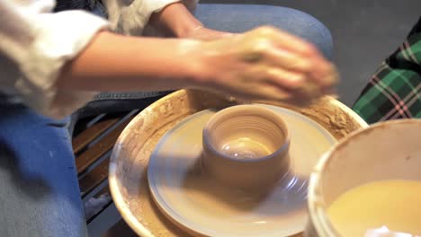 boy and woman works with pottery wheel in a workshop