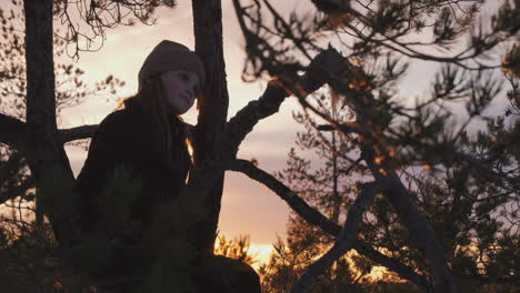 Happy-Girl-Sits-in-Tree,-Golden-Hour-Sunset